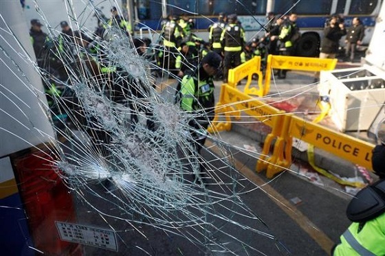 憲法裁の近くで負傷者が出た現場で、窓ガラスを割られたバス＝１０日、ソウル（ロイター）
